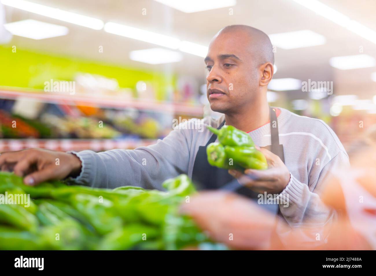 Spanish employee in vegetable store with green peppers Stock Photo Alamy