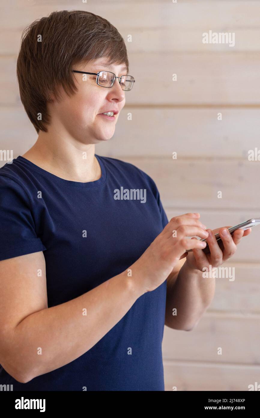 Woman holding, using smart phone and reading phone message. Hands holding mobile phone and typing. Taken from hand.  Stock Photo