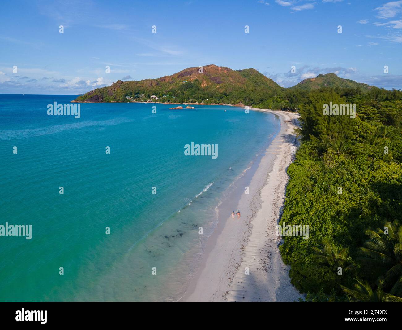 Drone aerial view of the beach of Praslin Seychelles Anse Volbert, couple of men and women walking at the beach.  Stock Photo