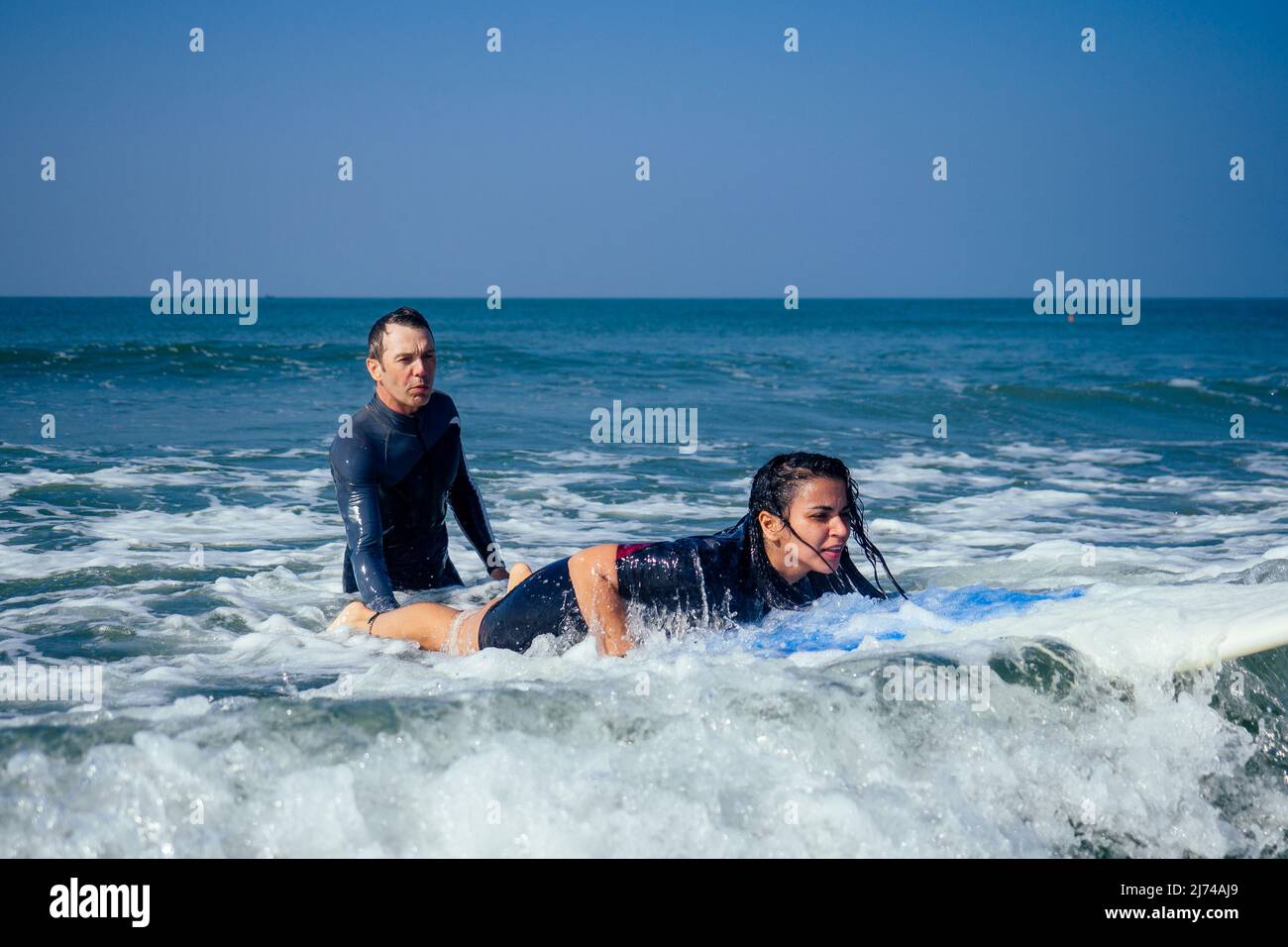 man instructor demonstrating how to stand up on surfboard to indian