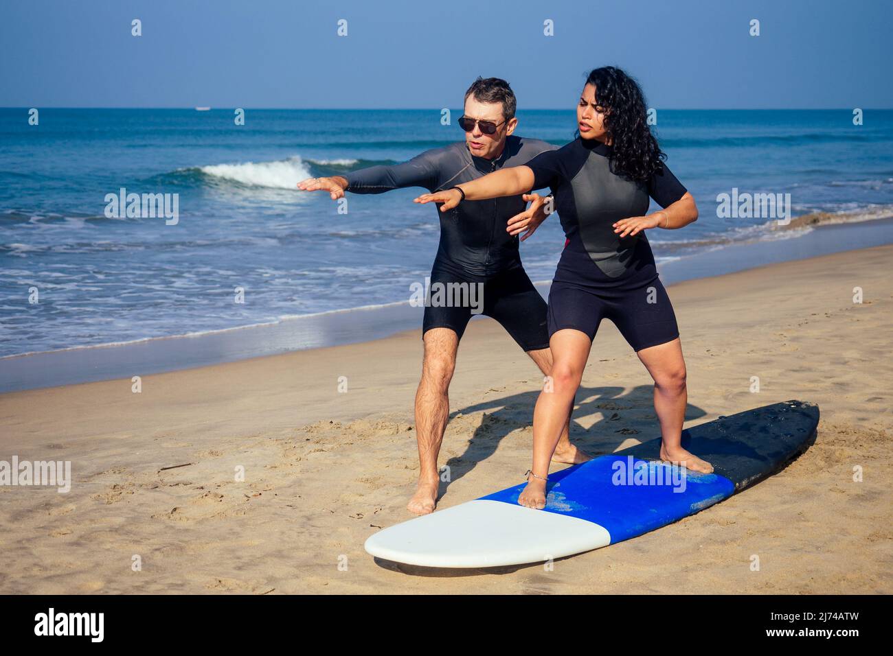 man instructor demonstrating how to stand up on surfboard to indian