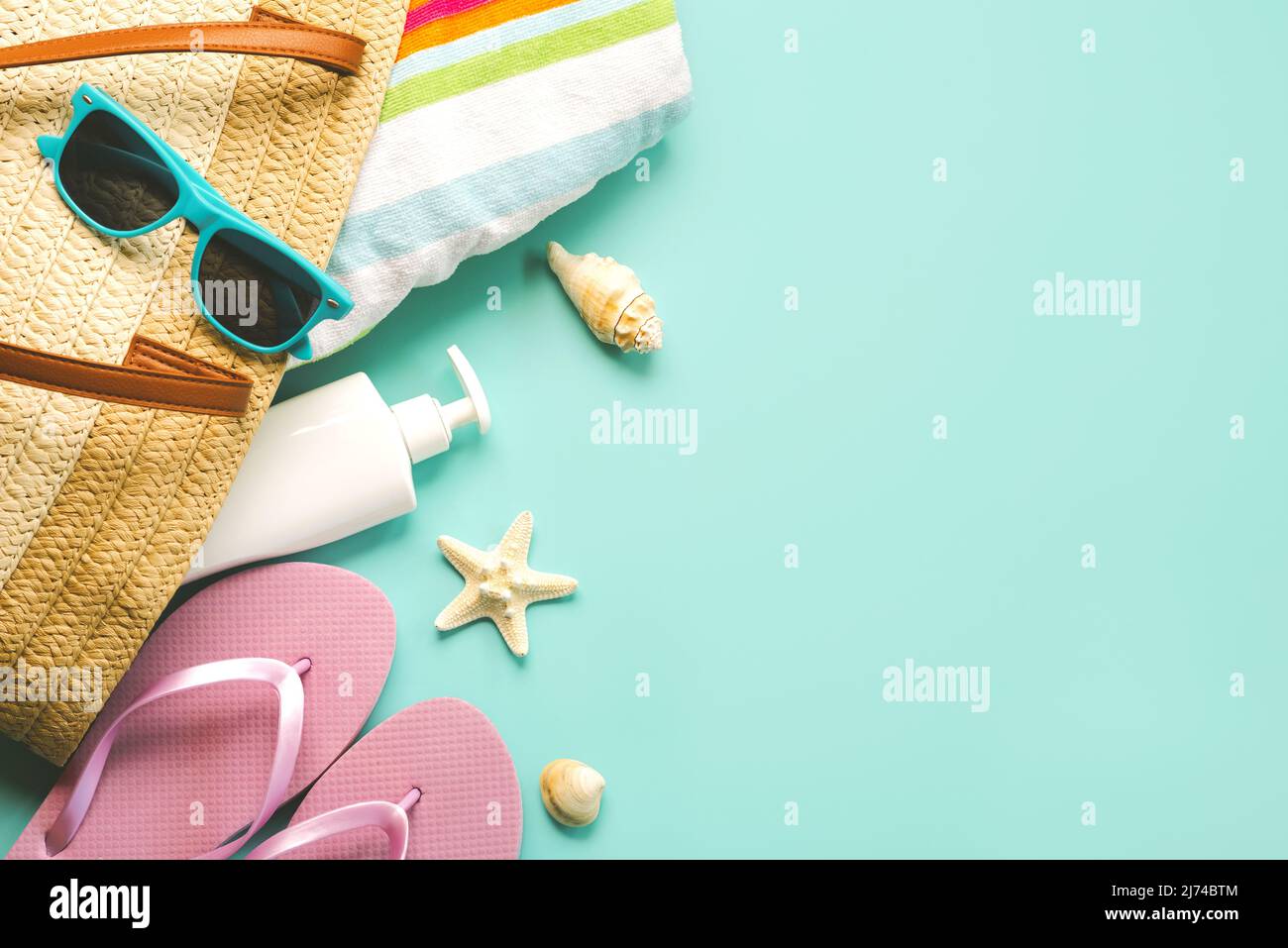Summer holiday concept.Top view of beach bag with flip flops,beach towel,sunglasses,sea shells,sunscreen and starfish with space for text over blue ba Stock Photo