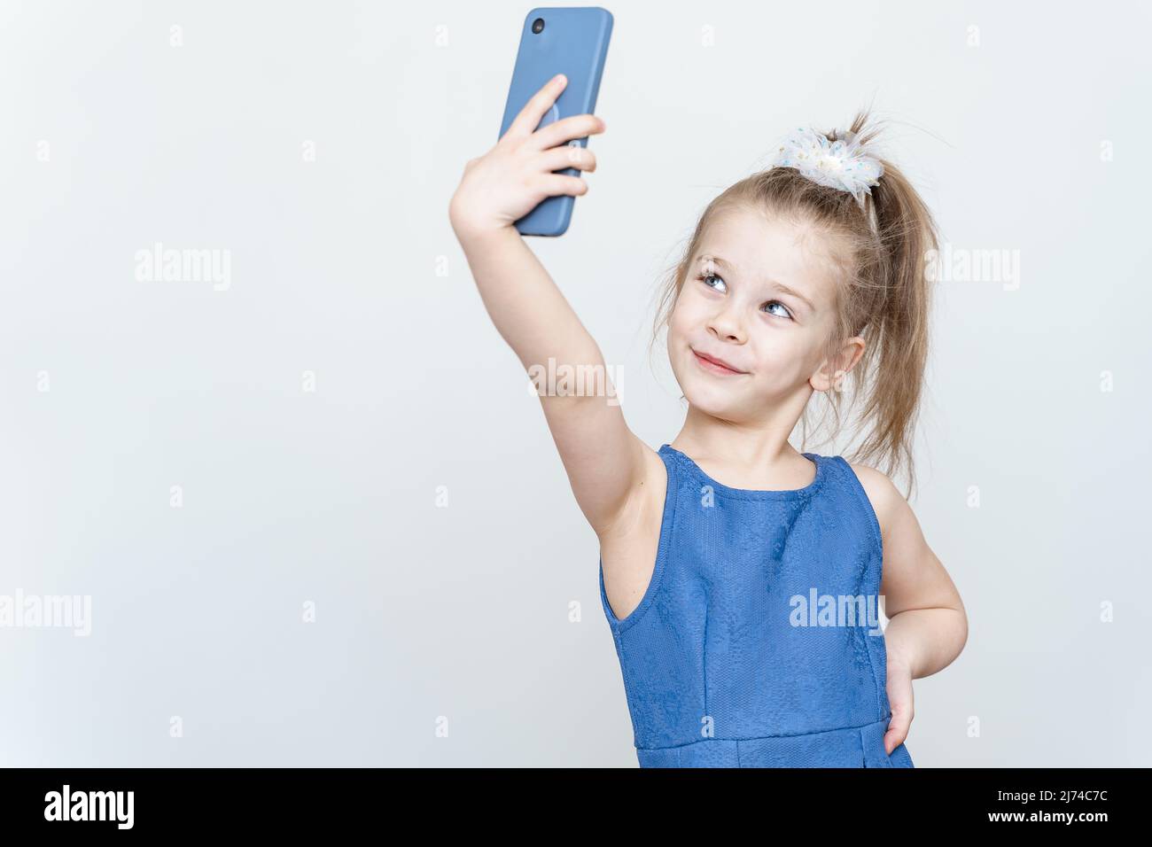 portrait of a cute 5 year old girl with a smartphone on a light ...
