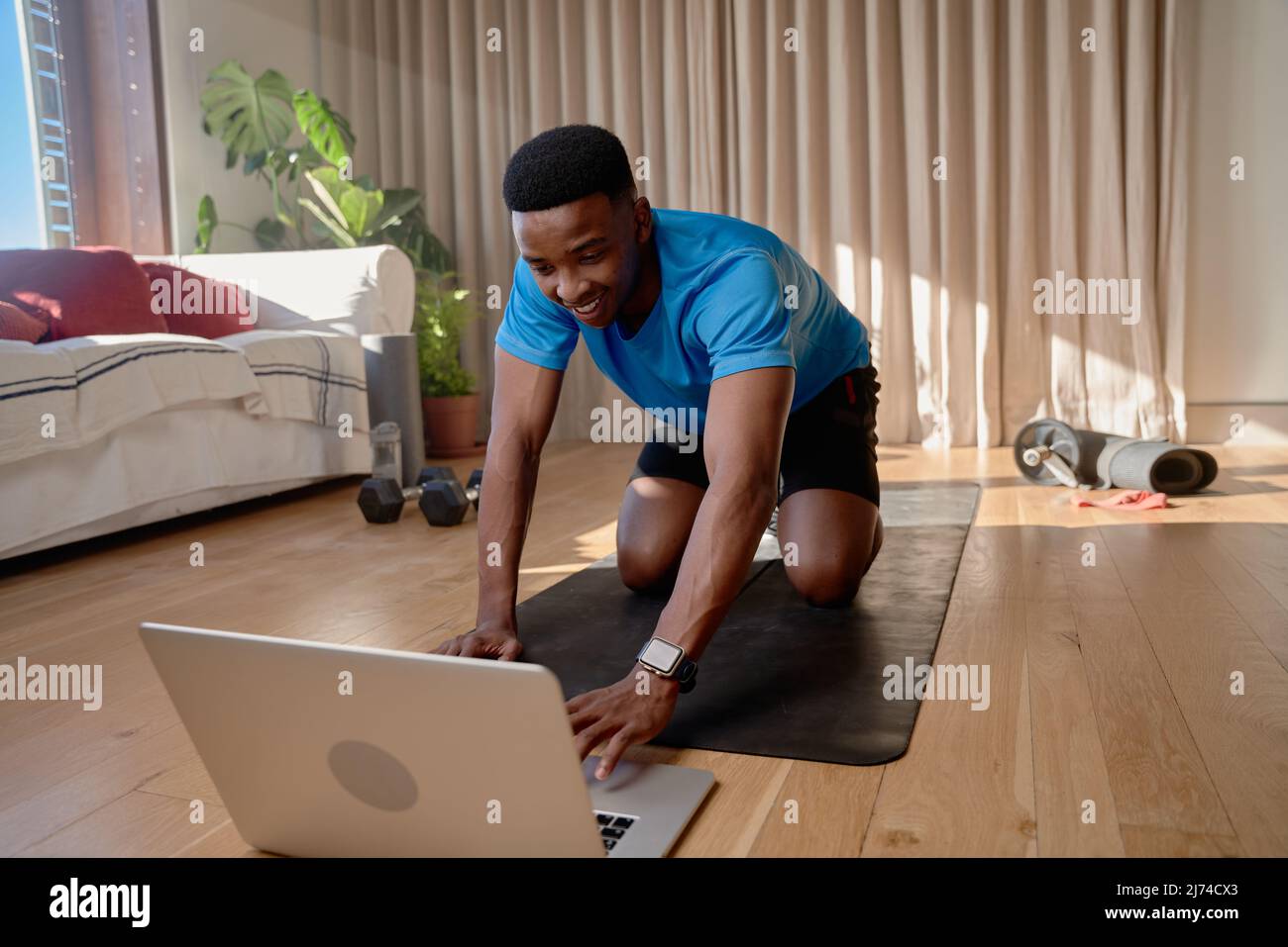 Young happy black African america male working out at home doing an online class using his laptop in his living room Stock Photo