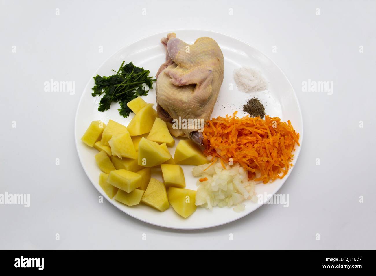 Fresh raw organic quail meat with ingredients for cooking healthy soup. Raw quail bird, fresh cut potato, carrot, onion, frozen parsley and spice on t Stock Photo