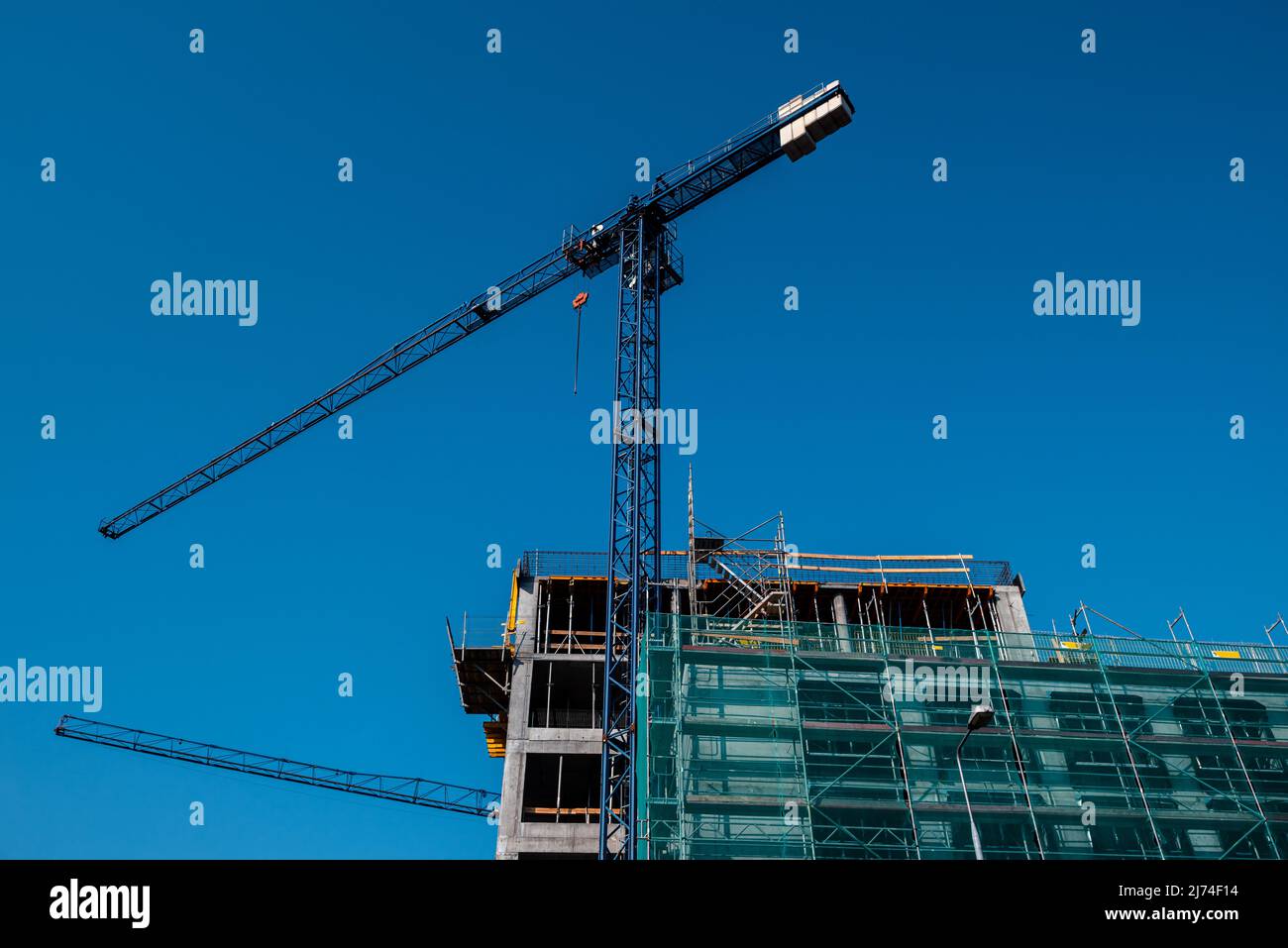 Unfinished building and tower crane on sky background. Stock Photo