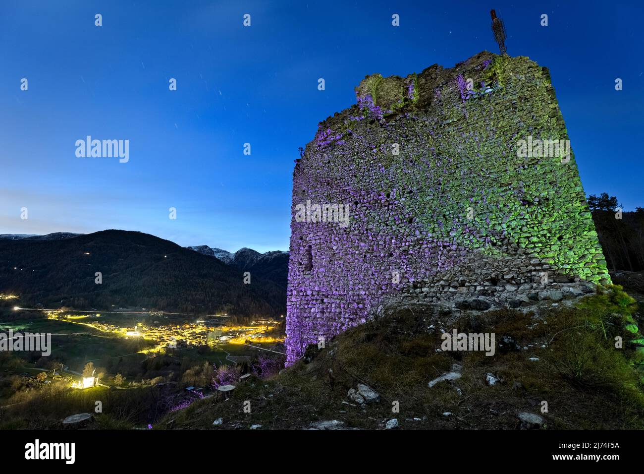 Ghostly night at the medieval ruins of San Pietro castle. In the background the village of Torcegno. Valsugana, Trento province, Trentino Alto-Adige, Stock Photo