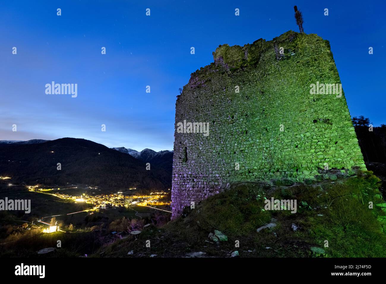 Ghostly night at the medieval ruins of San Pietro castle. In the background the village of Torcegno. Valsugana, Trento province, Trentino Alto-Adige, Stock Photo