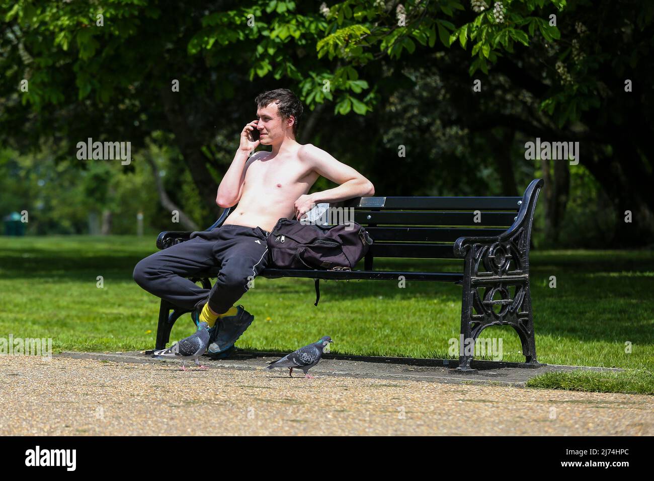 London, UK 05 May 2022 - A topless man sitting on a park bench in Finsbury Park, north London on a warm and sunny day. According to the Met Office, a high of 20 degrees celsius is forecast for today. Credit Dinendra Haria /Alamy Live News Stock Photo