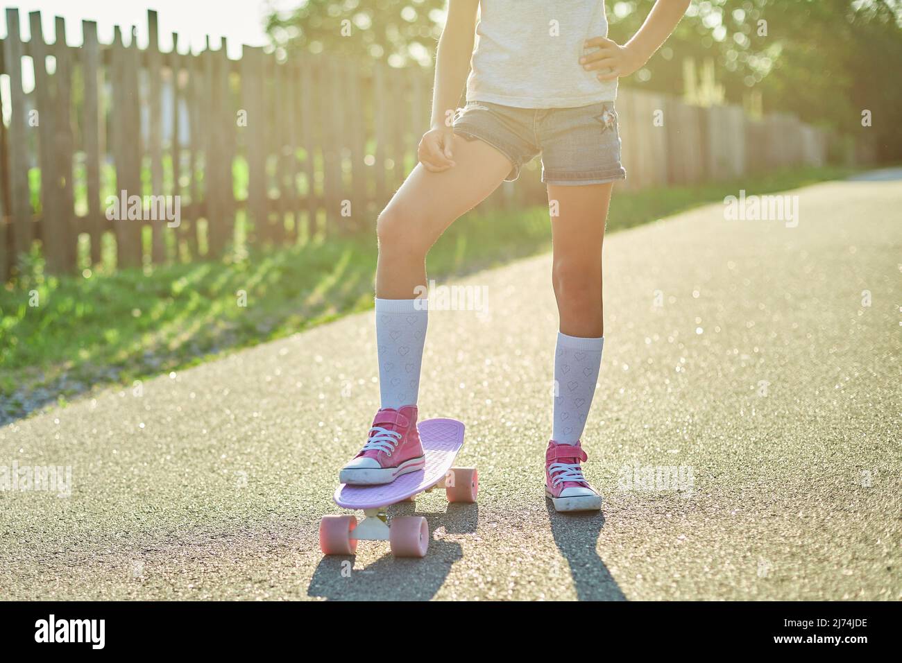 Little girl learning to use a skateboard, anonymous child wearing white socks and pink shoes