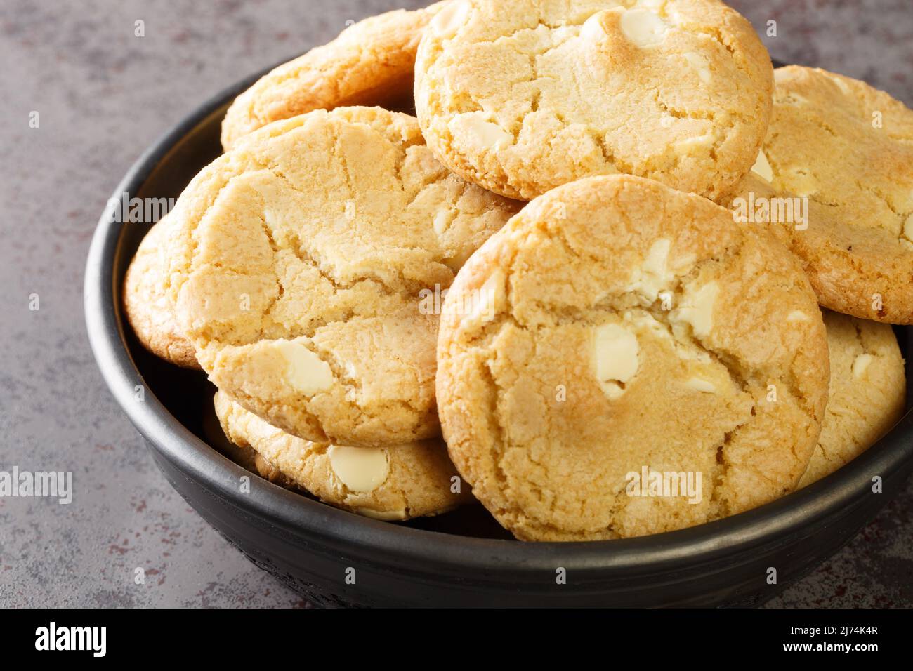 White chocolate biscuit cookies and macadamia nuts in the plate on the table close-up. Horizontal Stock Photo