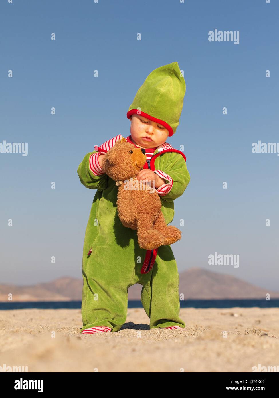 Kleinkind steht am Strand mit Teddy im Arm Stock Photo