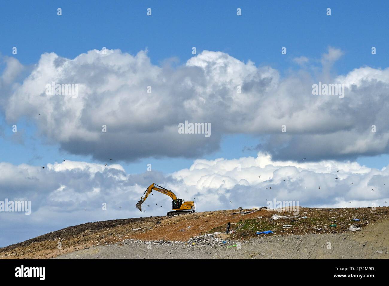 Swindon, England - April 2022: Mechanical digger working on a site for dumping and burying household waste. Stock Photo