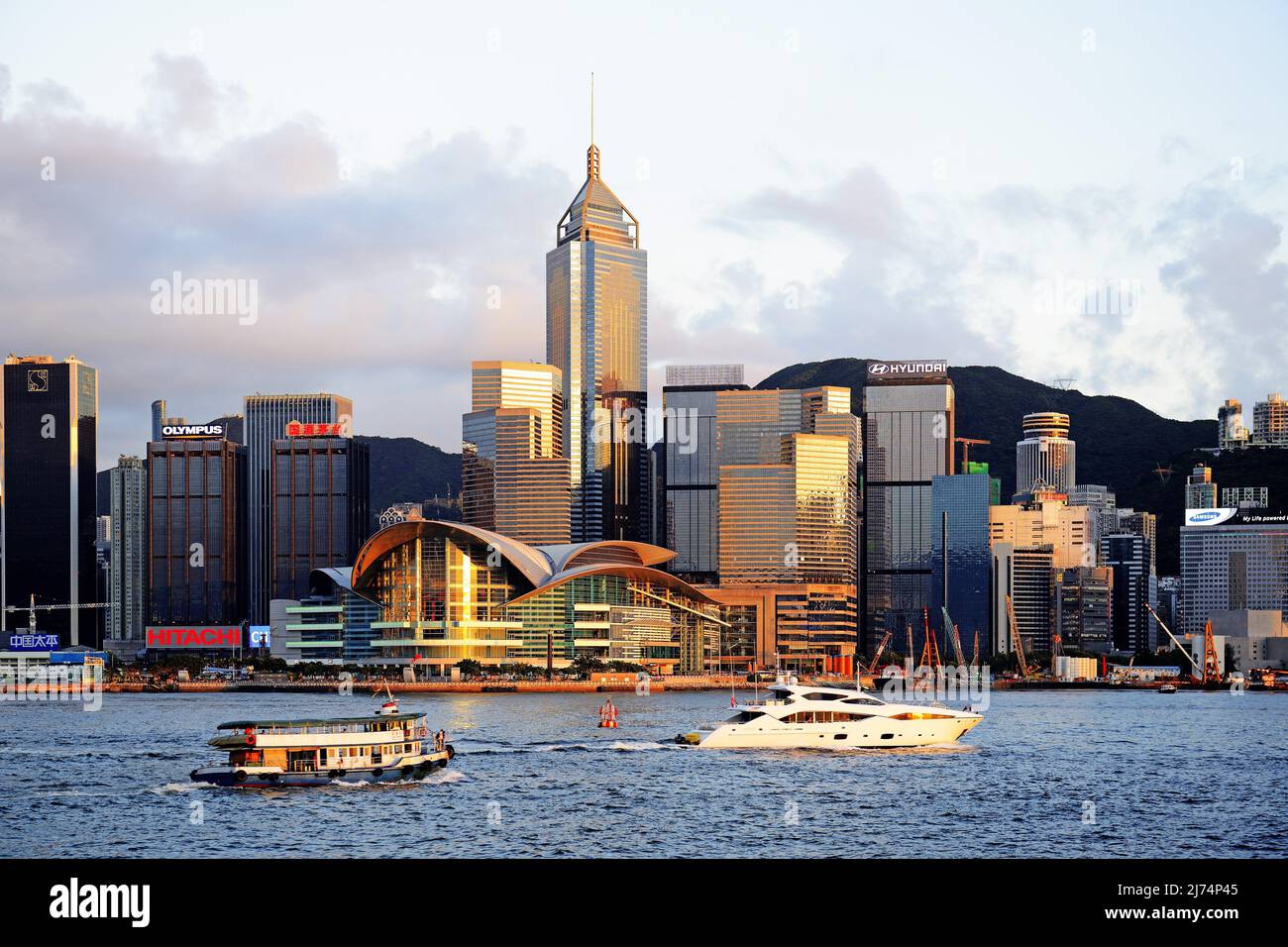View from Kowloon onto the Skyline of Hongkong Island at the Hongkong River with boats at sunset, China, Hong Kong Stock Photo