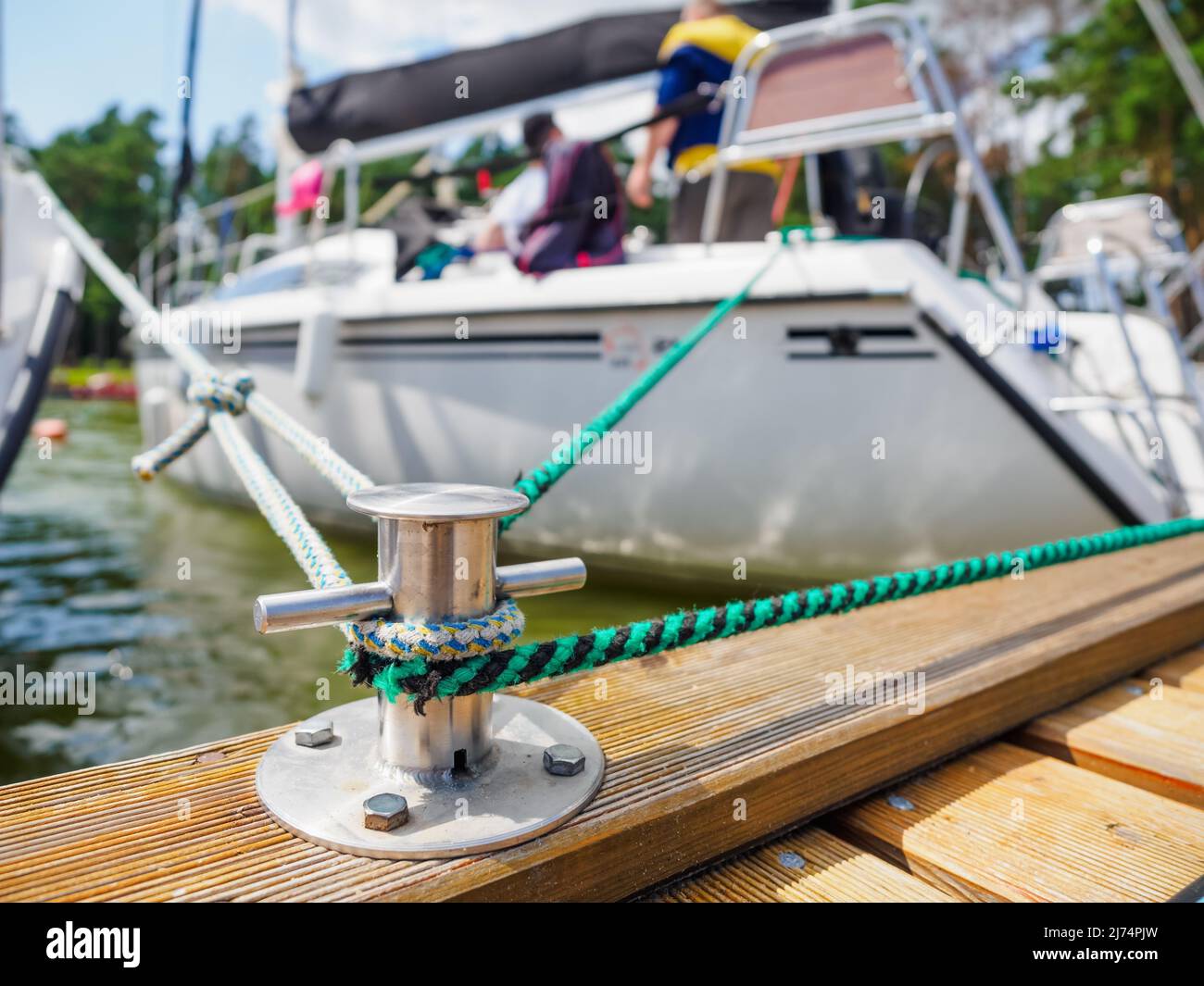 A white sailing boat moored with a line tied around a metal fixing. Mooring  rope and bollard for recreational boats at the harbor. Close up photo of m  Stock Photo - Alamy