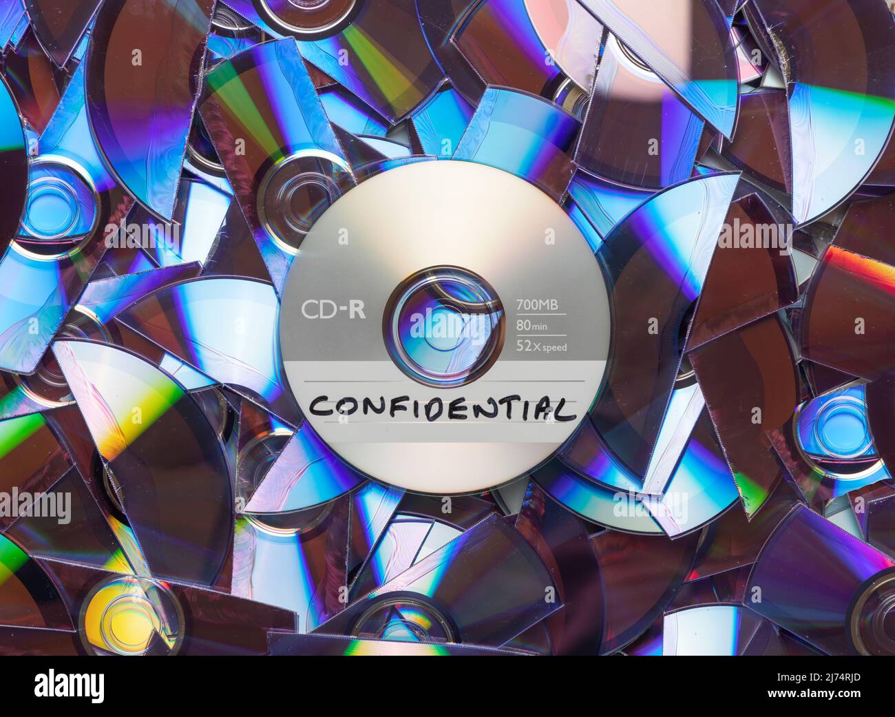 CD with confidential written on it, with shredded CD's and DVD's in the background. Stock Photo