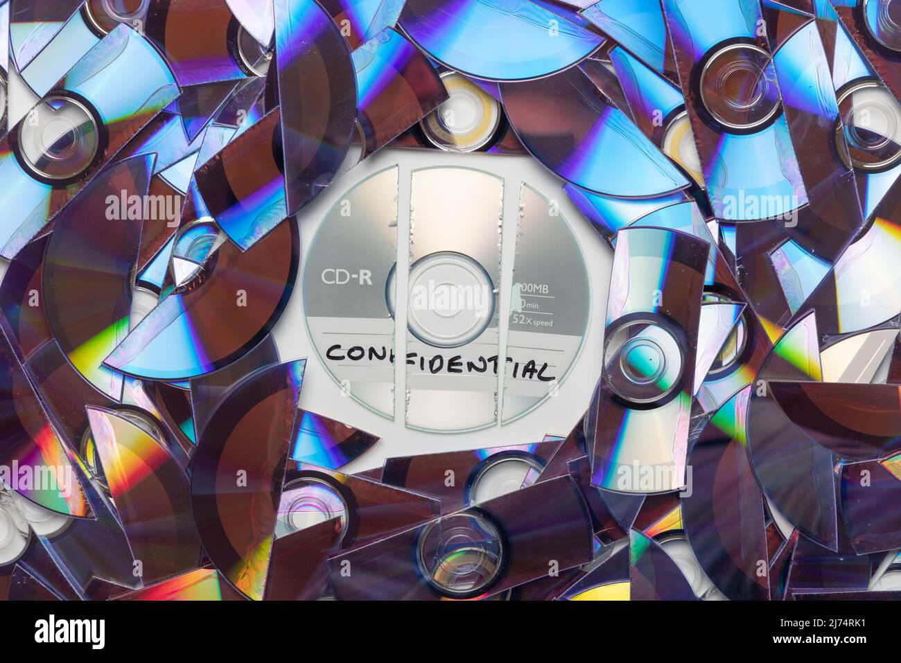 CD with confidential written on it, with shredded CD's and DVD's in the background. Stock Photo