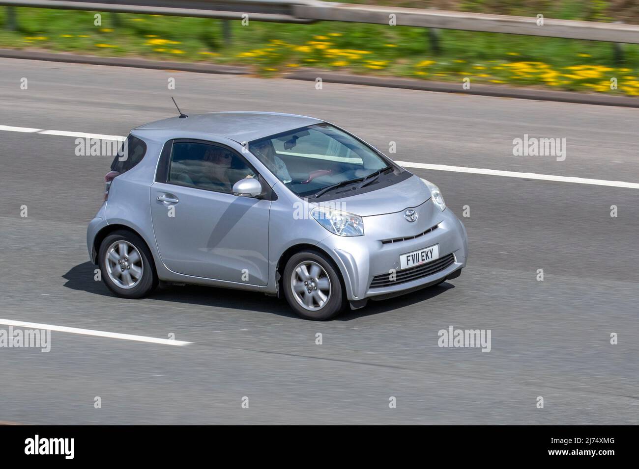 2011 silver TOYOTA IQ VVT-1 988cc petrol 5 speed manual small city car; driving on the M61 near Manchester, UK Stock Photo