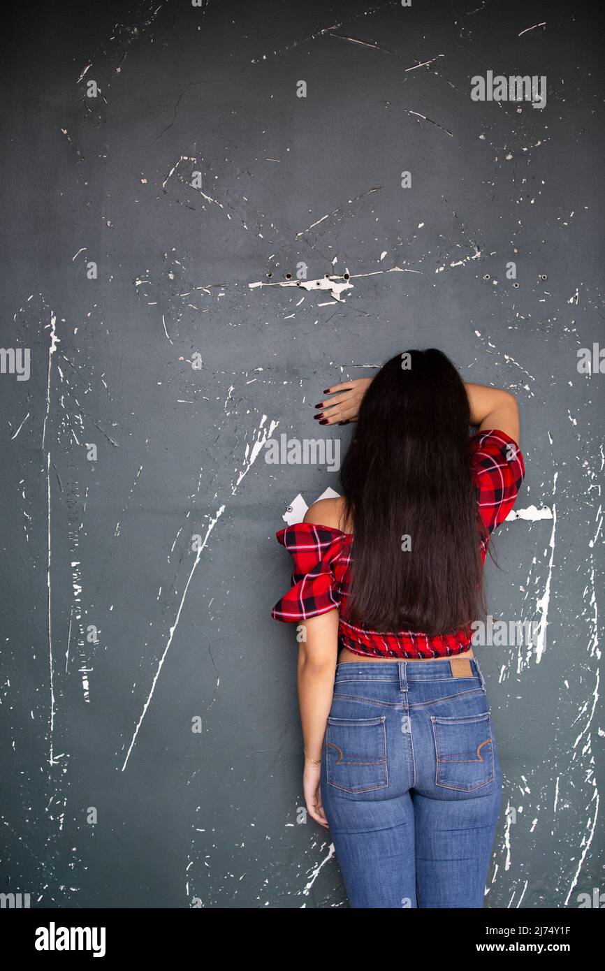 Rear view of woman crying against the wall Stock Photo