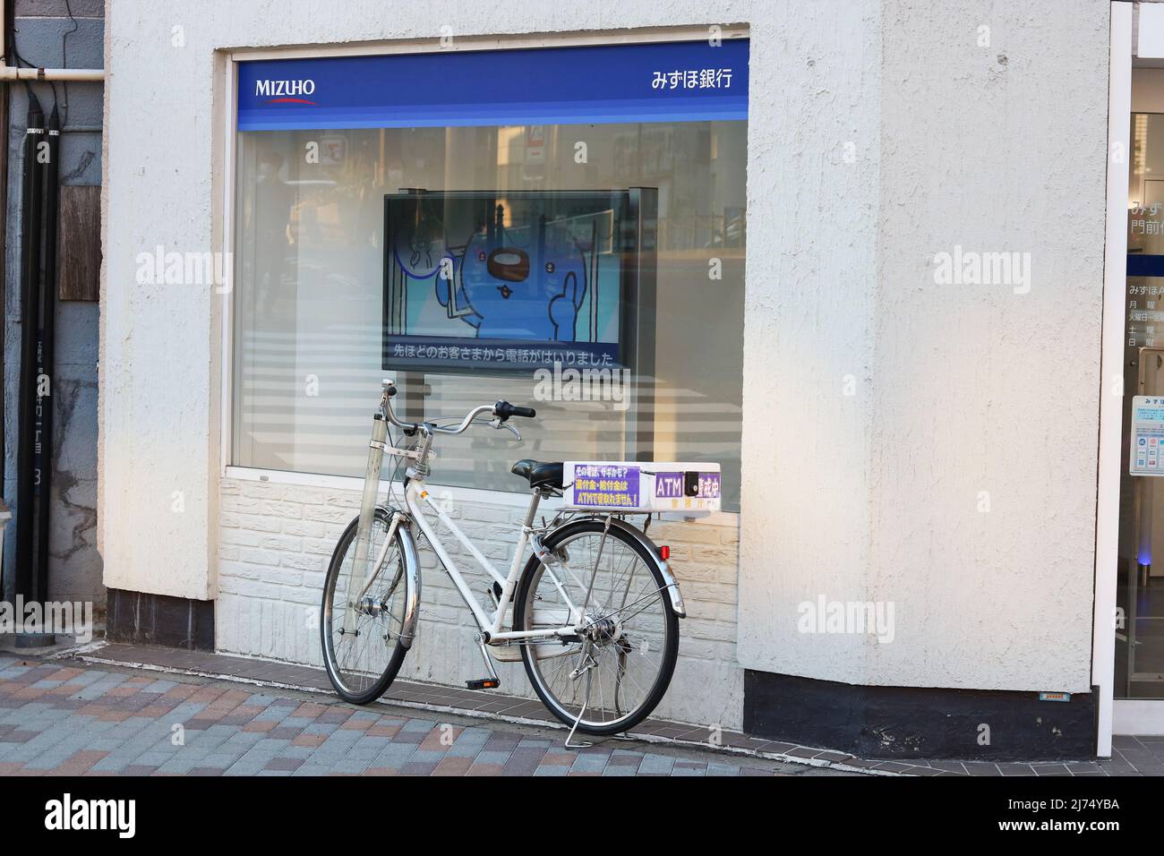 TOKYO, JAPAN - May 3, 2022: Mizuho Bank ATM facility with a police bicycle outside warning people about telephone scammers. It's in Tokyo's Koto Ward. Stock Photo
