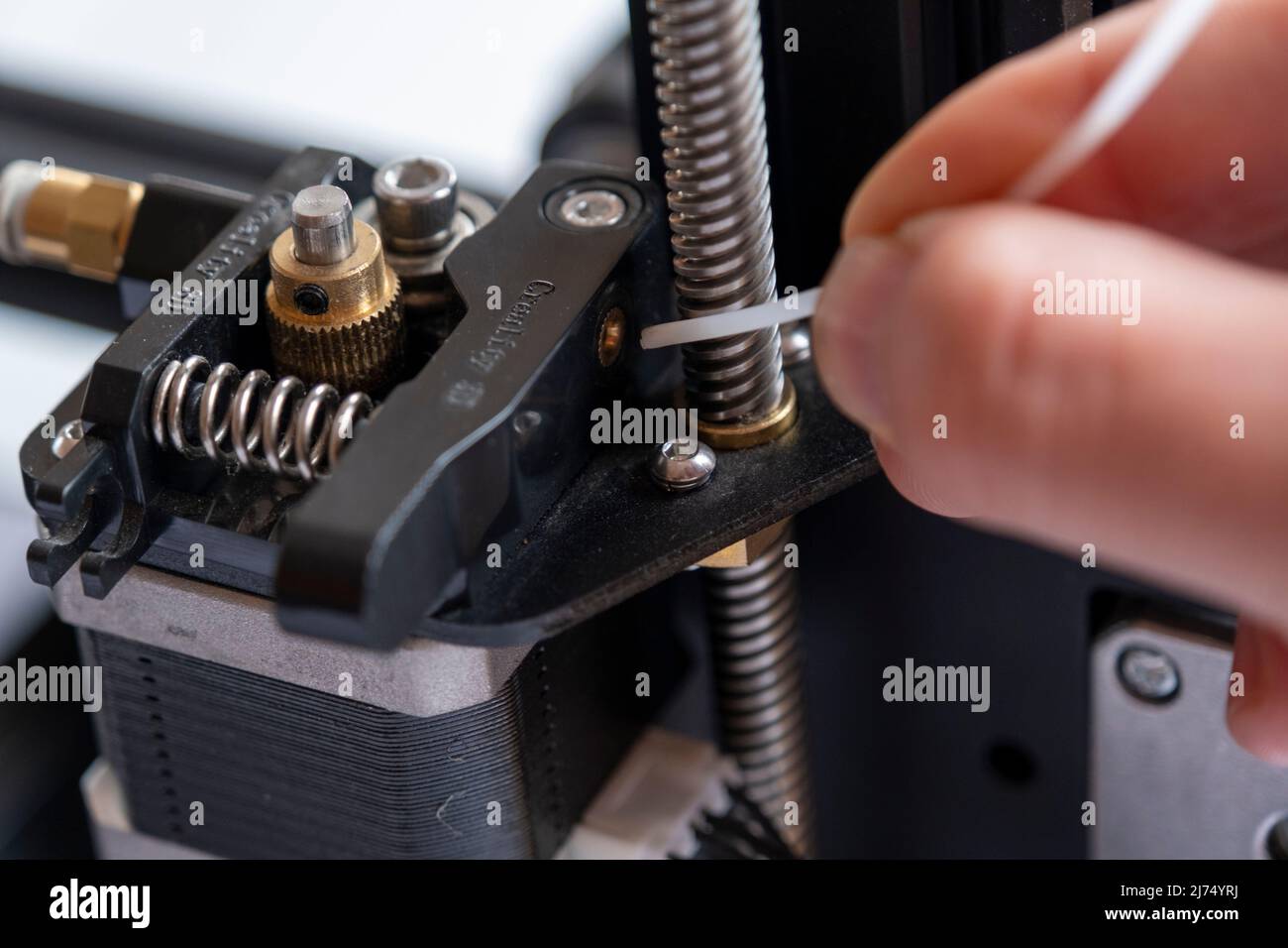 Man hand sets filament for 3D printer,  3D printer step motor and macro-shot of filament entry, printing concept, industrial machine, technological de Stock Photo