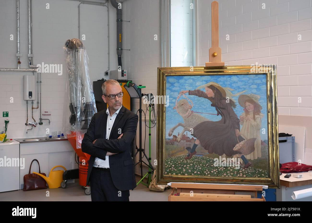 06 May 2022, Brandenburg, Potsdam: Christoph Martin Vogtherr, General Director of the Prussian Palaces and Gardens Foundation Berlin-Brandenburg (SPSG), looks at the painting 'Schäfchen' (oil on wood, 1905) by Thomas Theodor Heine in the Central Art Depository. The SPSG gave the painting to the relatives of the original owner, Irene Beran, who live in Great Britain, 81 years after it was expropriated by the Nazis. The house and collection of Beran, who lived in Brno, had been expropriated as Jewish property by the German occupiers in 1941. Photo: Soeren Stache/dpa Stock Photo