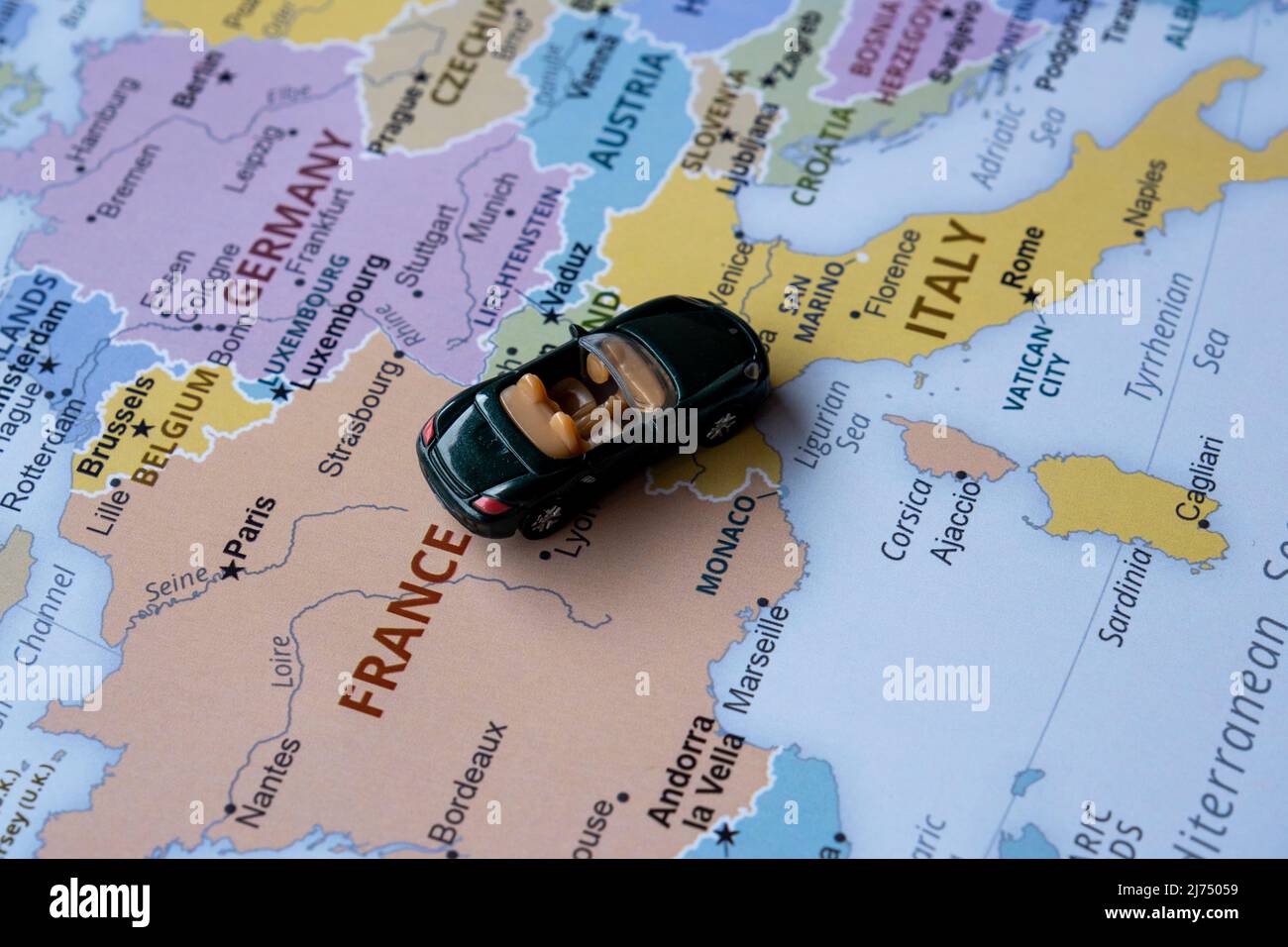 Toy car travels on Europe map, sitting view, vacation and destination concept, miniature green sport car going to France from Italy, worldwide tour Stock Photo