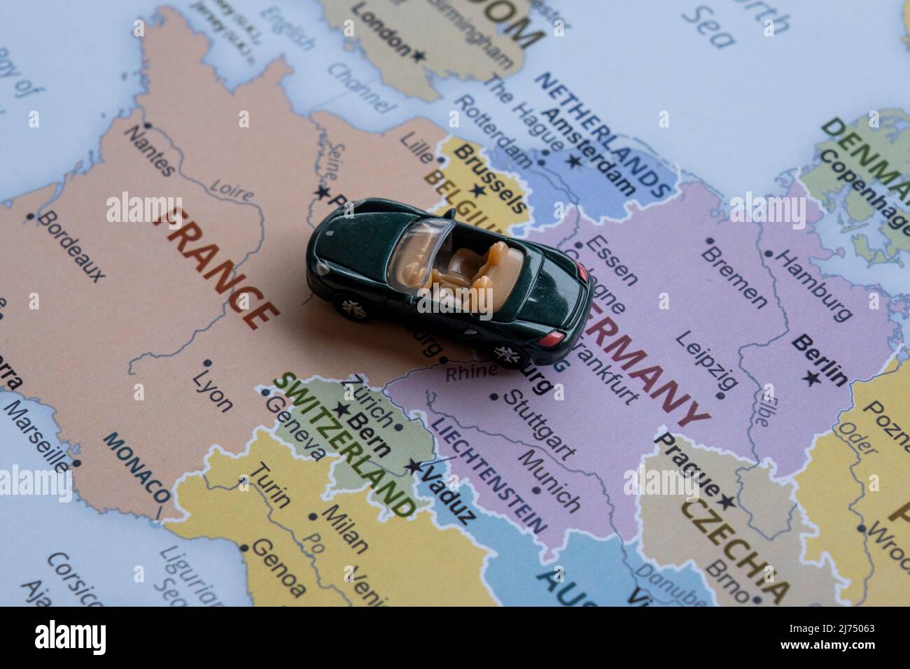 Toy car travels on Europe map, sitting view, vacation and destination concept, miniature green sport car going to France from Germany, worldwide tour Stock Photo