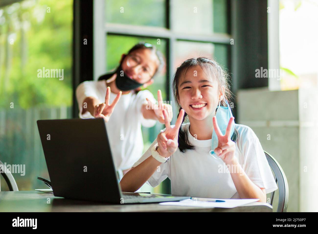 two asian teenager toothy smiling with happiness face while take out of protection face mask Stock Photo