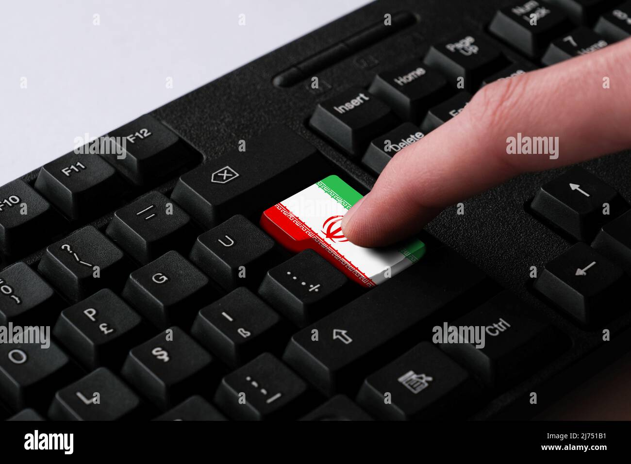 Pressing enter button with Iran flag, represents a cyber-attack of Iran, metaphor of learning Persian language, black keyboard close up Stock Photo