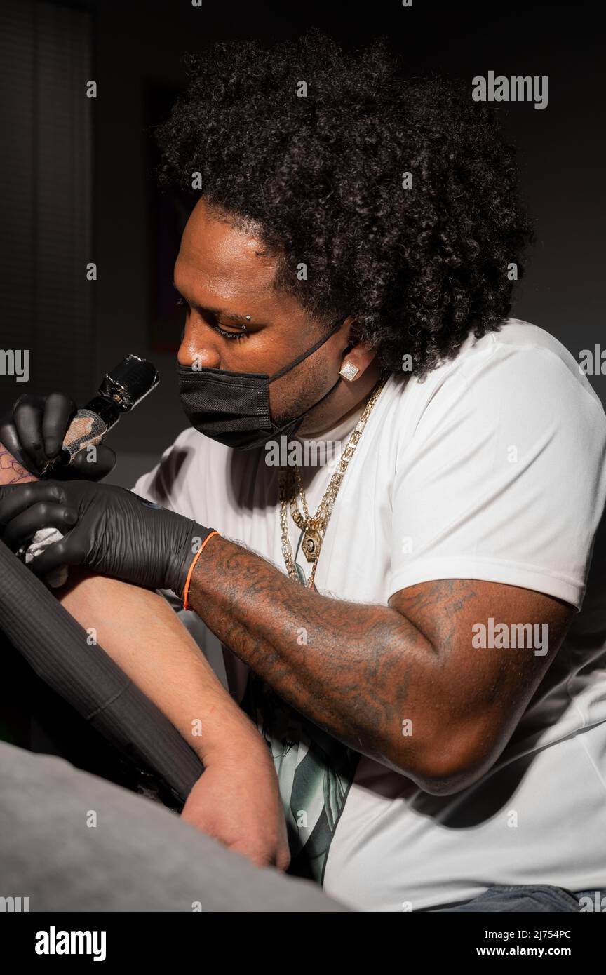 Professional African American tattoo artist makes a tattoo on client
