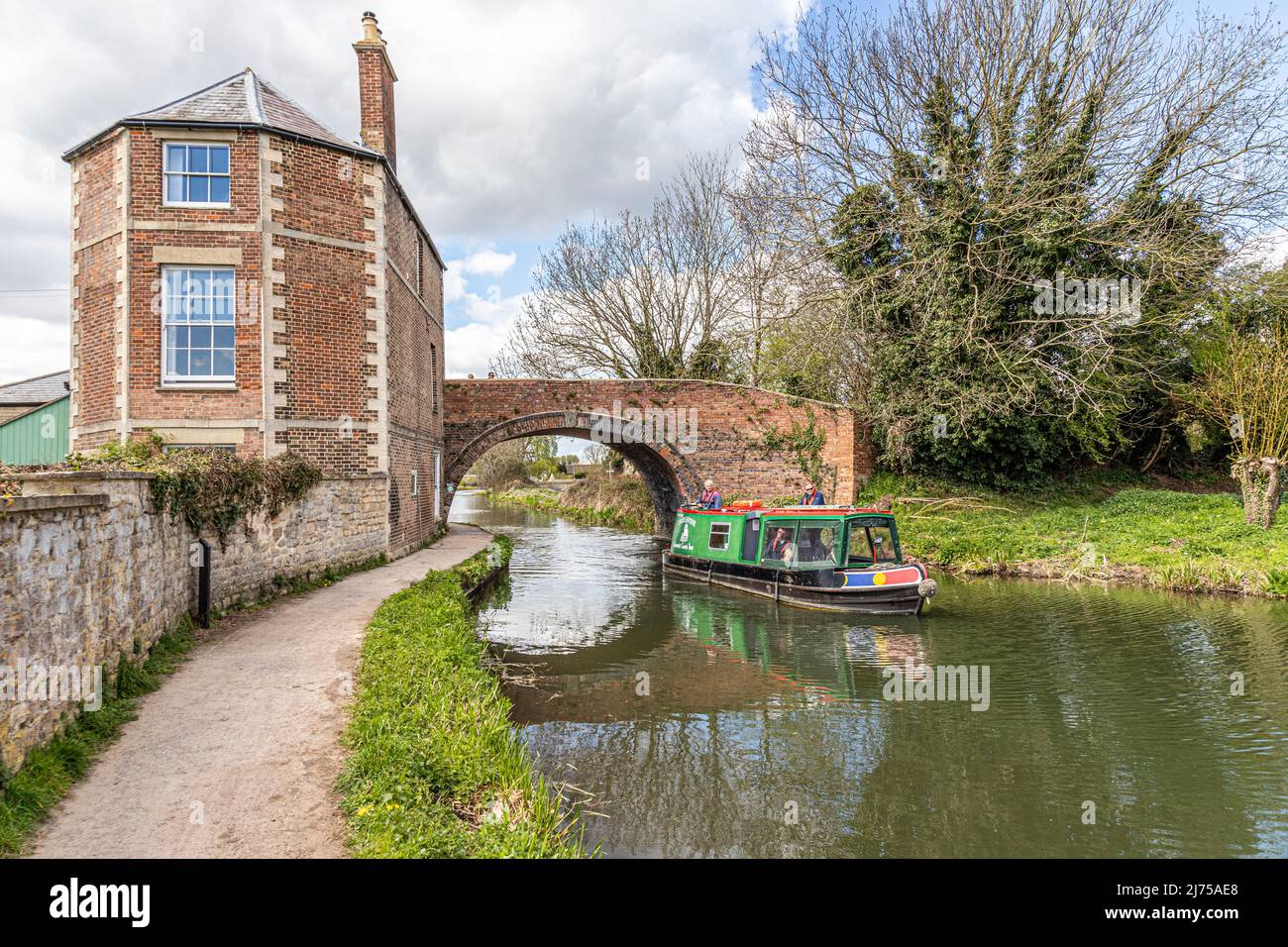 The Cotswold Canals Trust long boat Endeavour on the restored Stroudwater Canal passing Nutshell Bridge and House, Stonehouse, Gloucestershire, UK Stock Photo