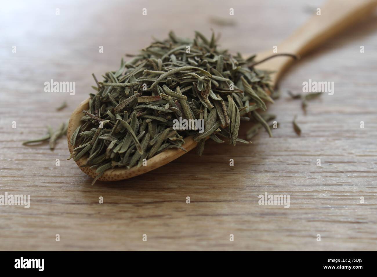 Dry rosemary in wooden scoop on table. Rosemary leaves prepared for herbal tea or traditional medicine. Stock Photo