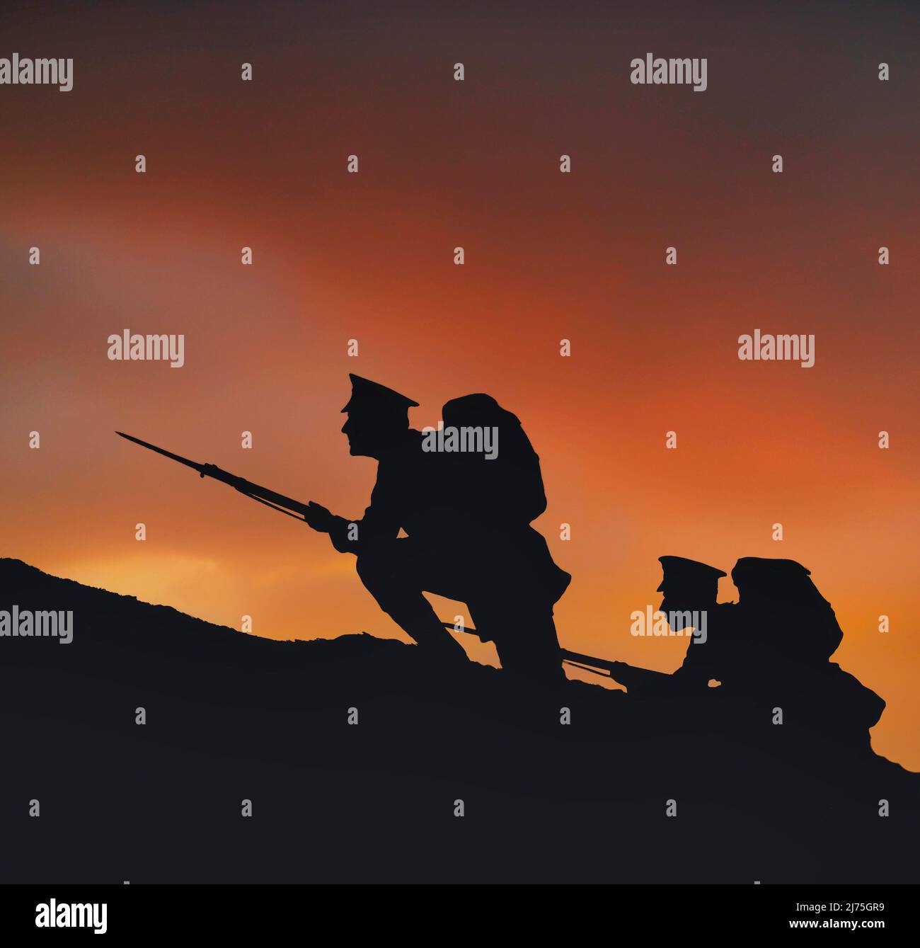 Two soldiers on a dawn raid with rifles and fixed bayonets. Silhouetted against a reddening sky, they climb a hill on the frontline during  World War One, 1914-1918. Stock Photo