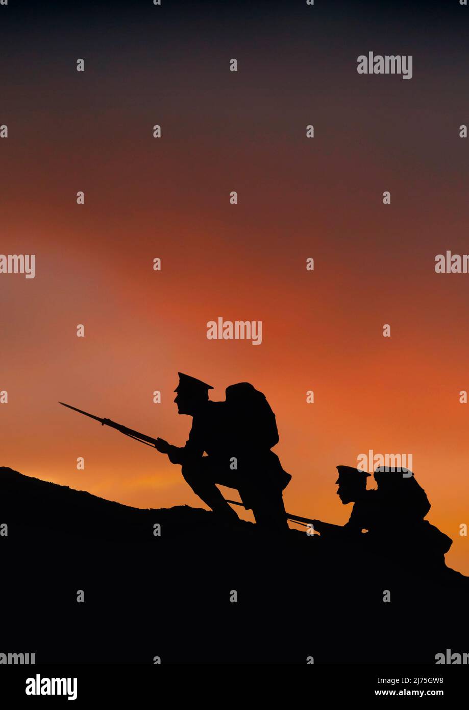 Two soldiers on a dawn raid with rifles and fixed bayonets. Silhouetted against a reddening sky, they climb a hill on the frontline during  World War One, 1914-1918. Stock Photo