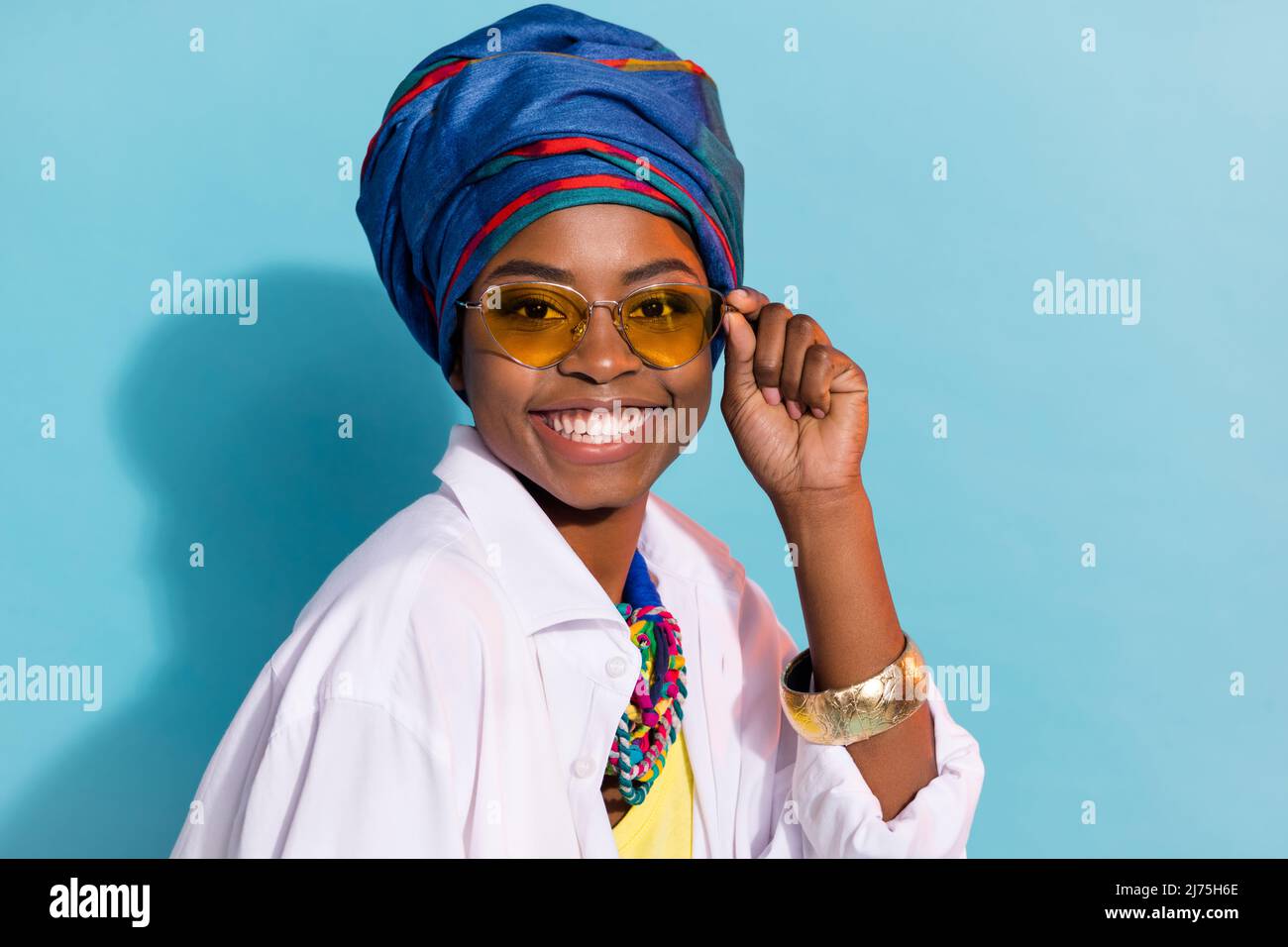 Portrait of gorgeous lady masai tribe look smiling wear national kenya outfit specs isolated blue color background Stock Photo