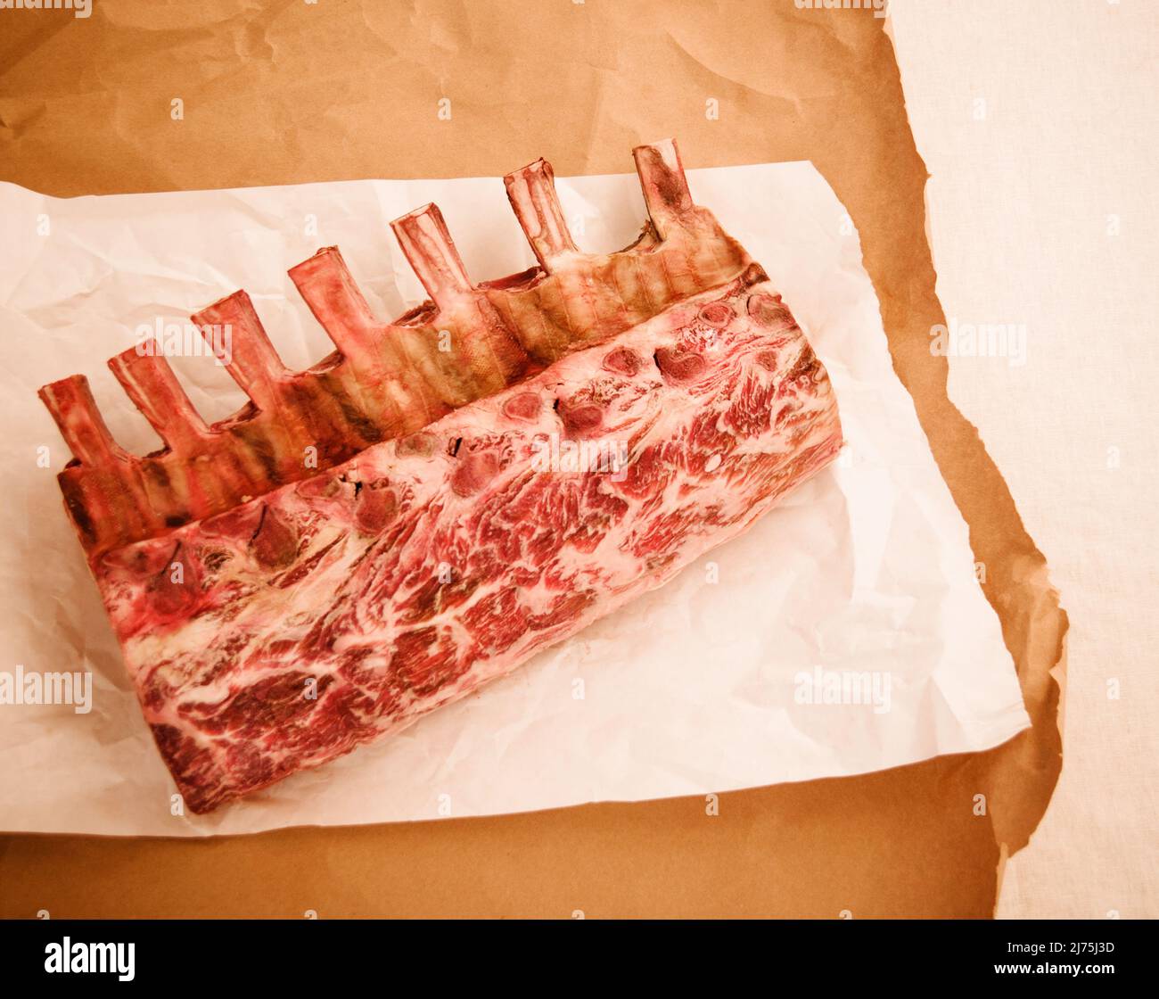 Raw aged Frenched prime rib roast on butcher paper Stock Photo