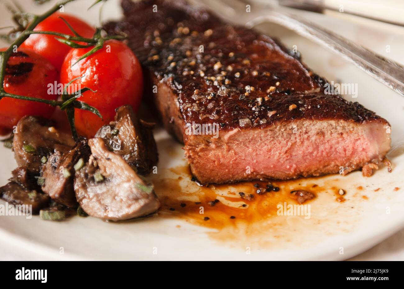 New York strip steak with roasted mushrooms and tomatoes Stock Photo
