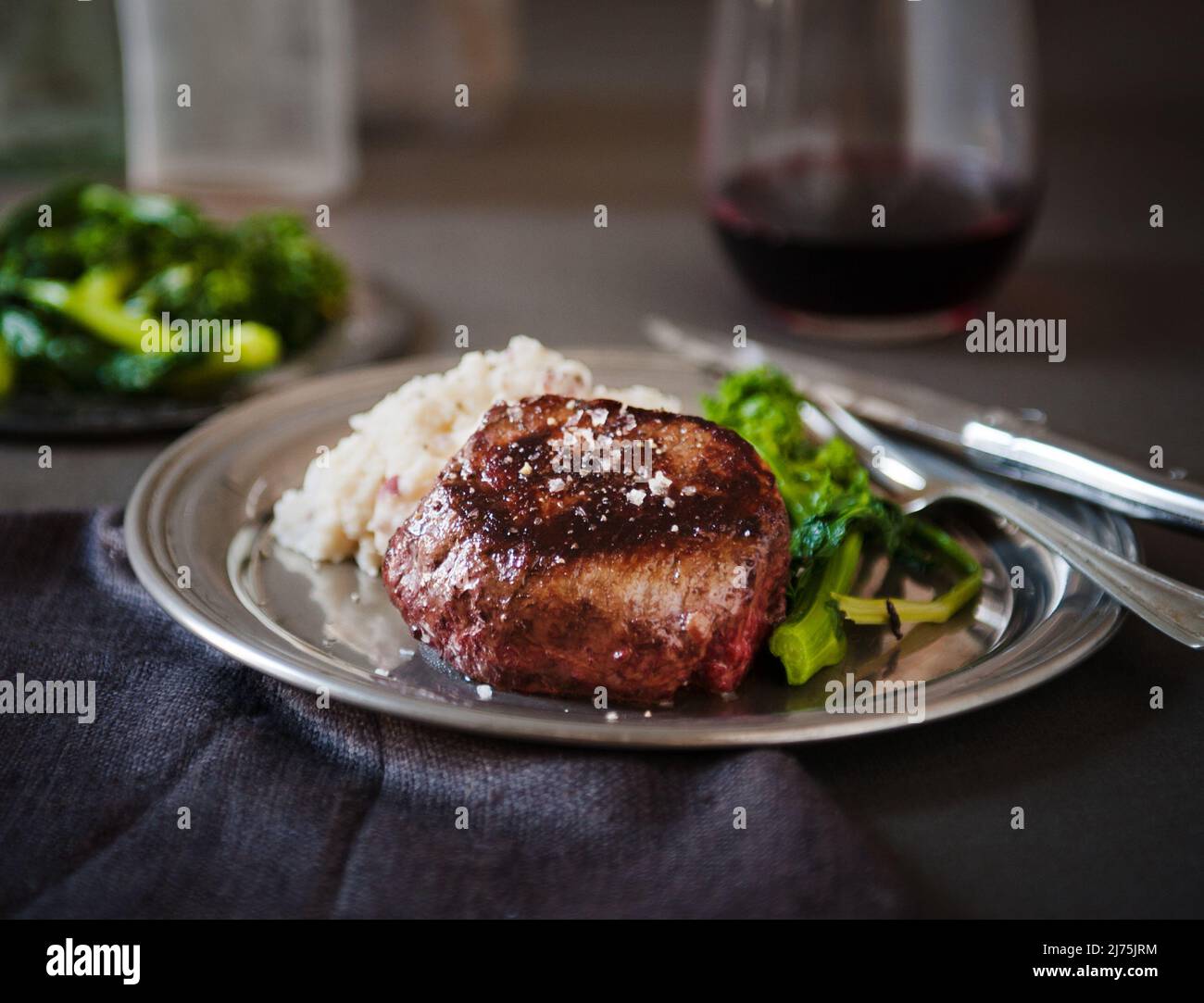 Filet Mignon with a Piece Pierced on a Fork; Served with Mashed Potatoes and Broccoli Rabe Stock Photo