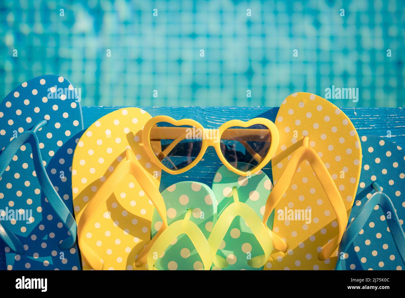 Beach flip-flops and sunglasses on blue wood against water background ...