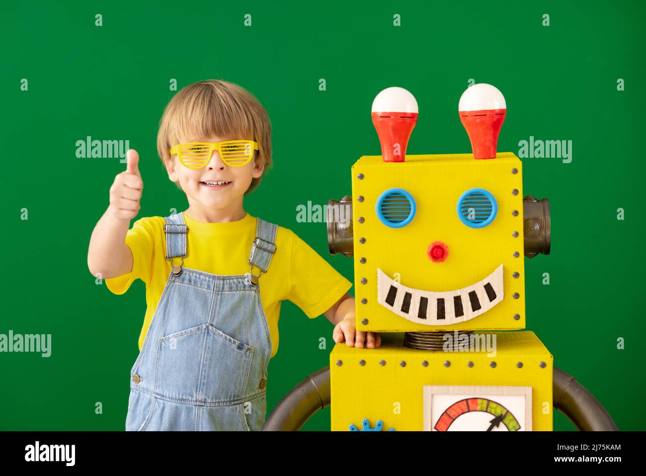 Happy child with toy robot at school. Funny kid against green chalkboard.  Education, creative and innovation technology concept Stock Photo - Alamy