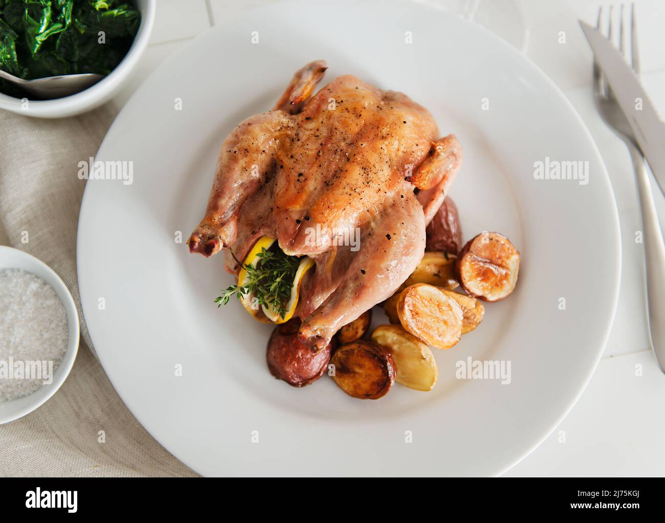 Roasted Lemon and Herb Stuffed Game Hen with a Side of Roasted Potatoes Stock Photo