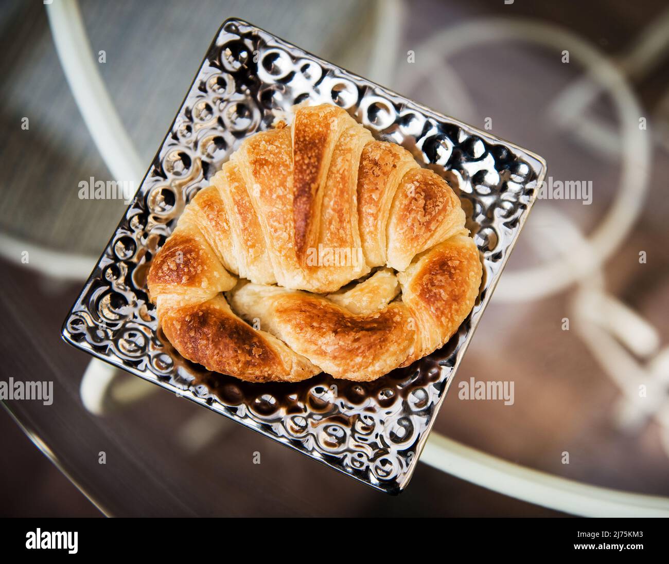 A croissant on a silver plate from above Stock Photo