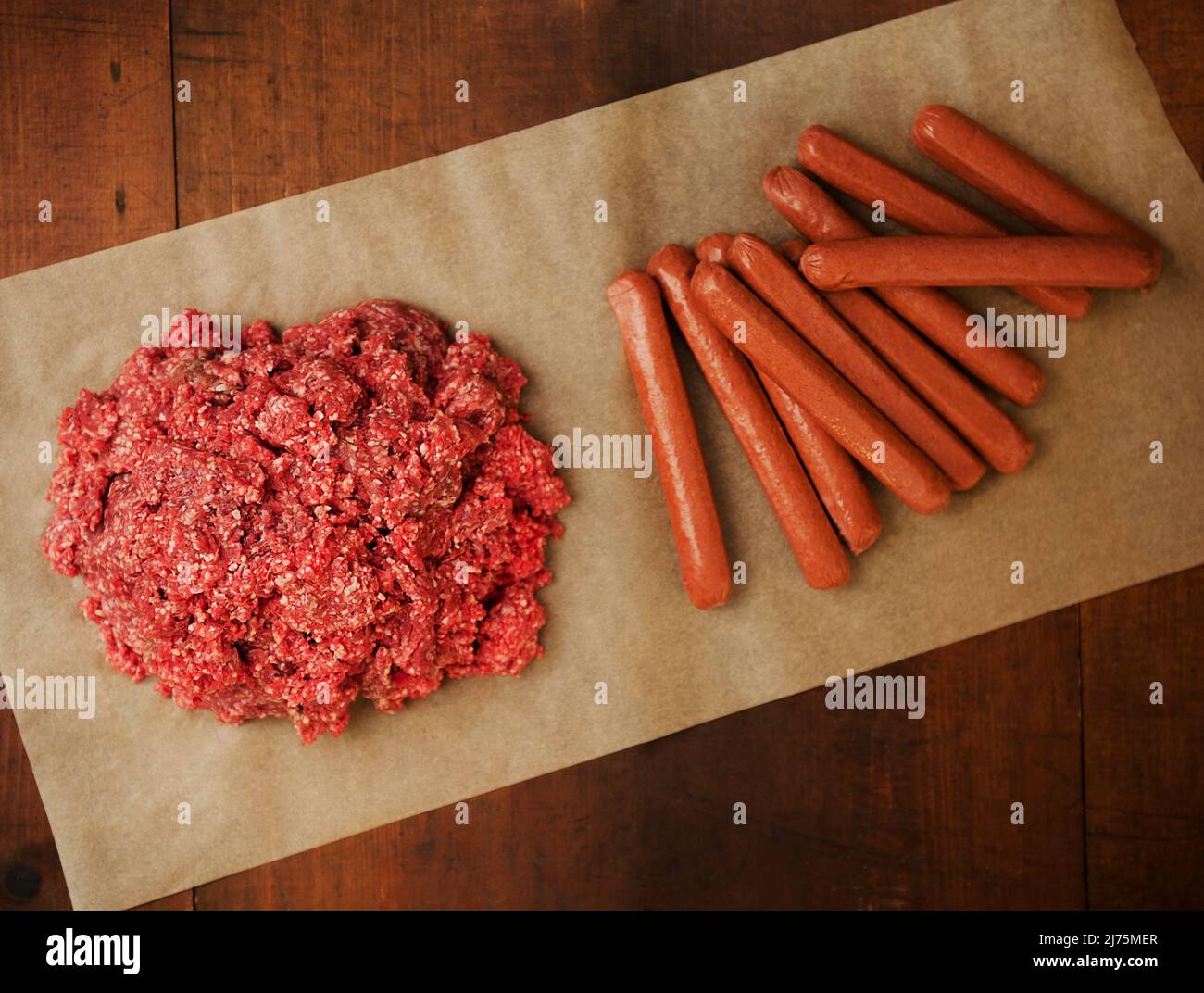 Raw Ground Burger and Hotdogs on Parchment Paper Stock Photo