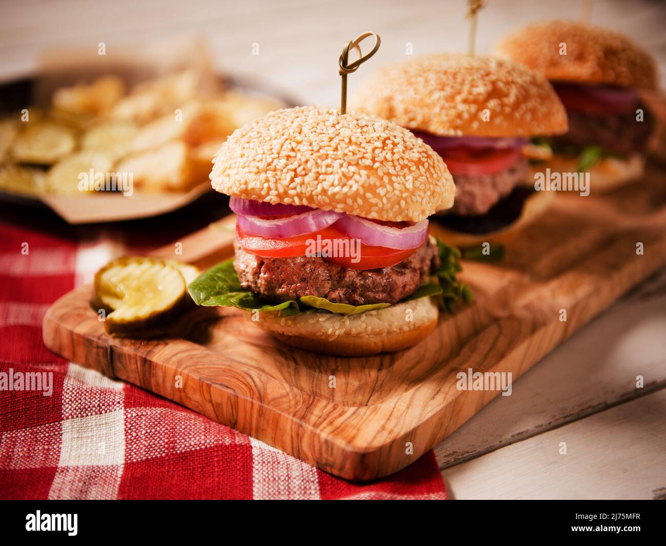 Tray of Hamburgers with onion, lettuce, tomato and pickles Stock Photo