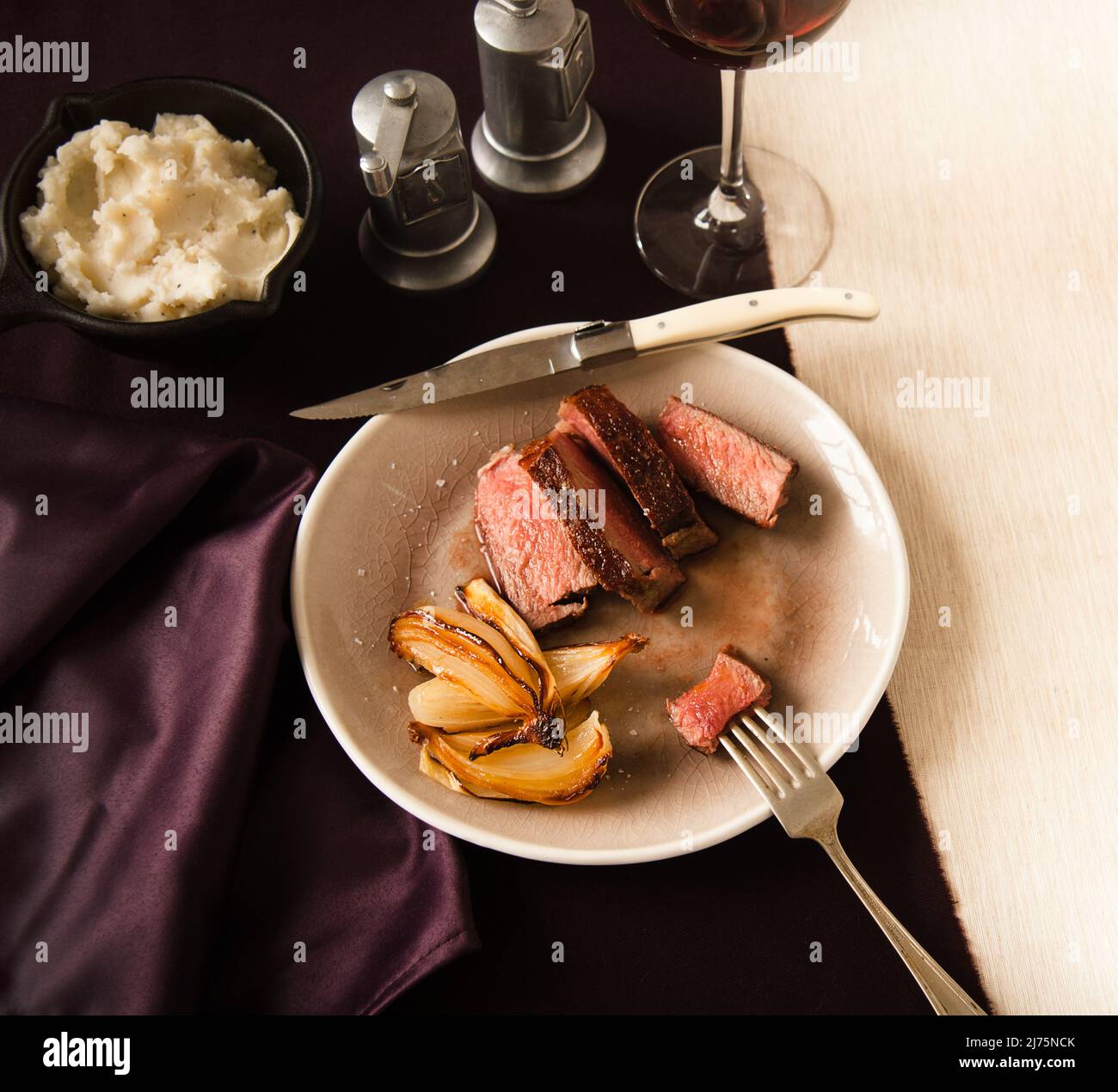 Sliced Steak and Onions in a Plate; Piece of Steak Pierced on a Fork