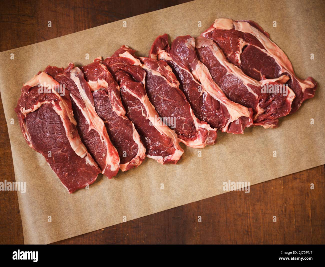 Raw Grass Fed Rib-Eye Steaks on Parchment Paper Stock Photo