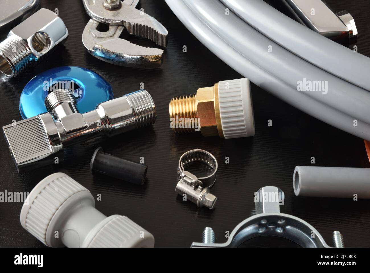 Detail of plumbing materials and tools on black workbench. Elevated view. Horizontal composition. Stock Photo