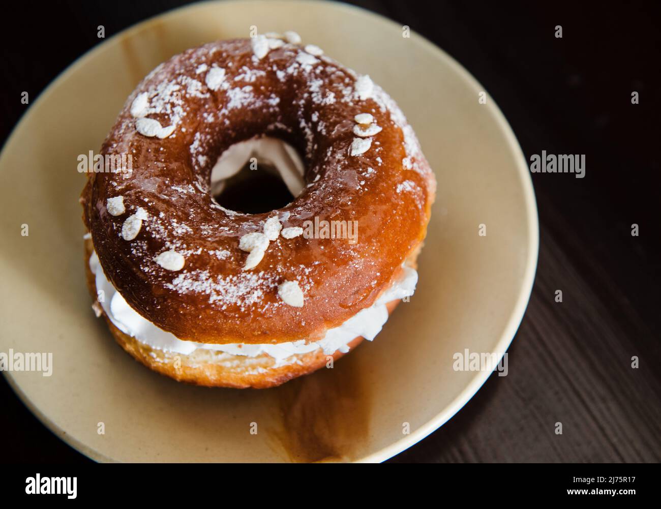 Glazed donut with whipped cream and powdered sugar Stock Photo