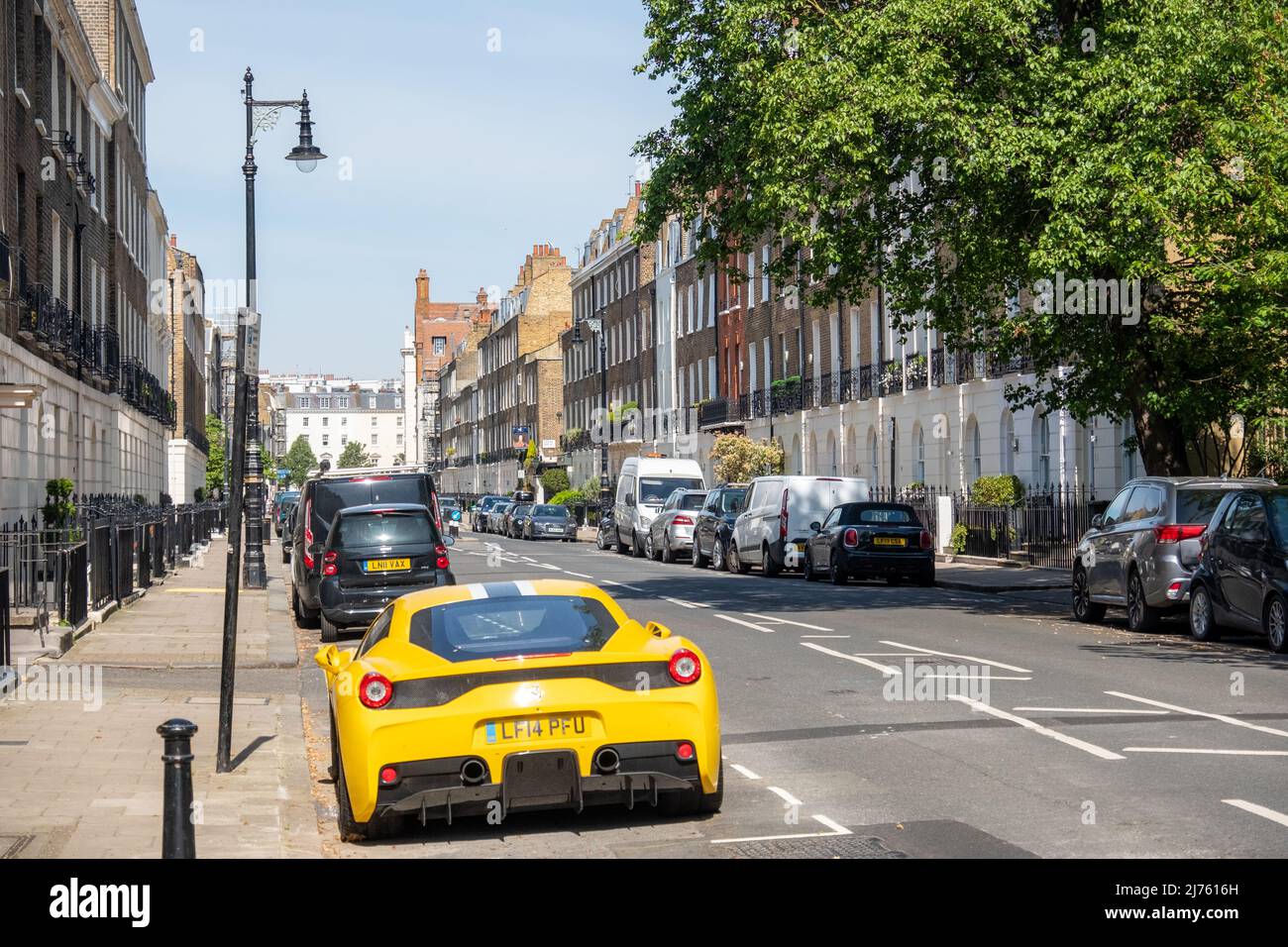 London- May 2022: A yellow Ferrari parked outside attractive townhouses in Knightsbridge, an affluent area of London. Stock Photo